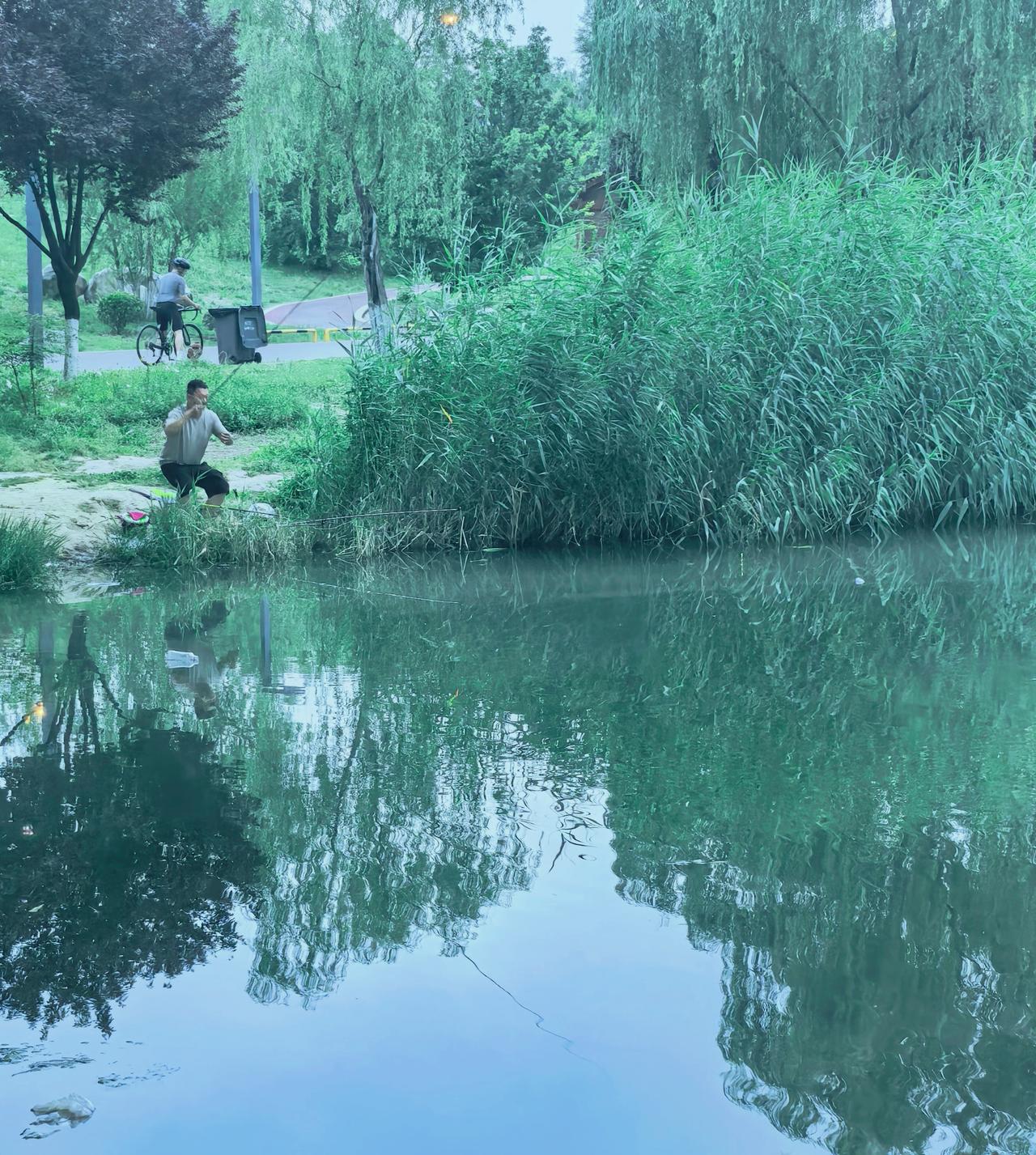 他蹲在池塘边像尊雕塑，
手中的钓竿完成逗号，
水草在水底写朦胧诗，
蜻蜓点水的瞬