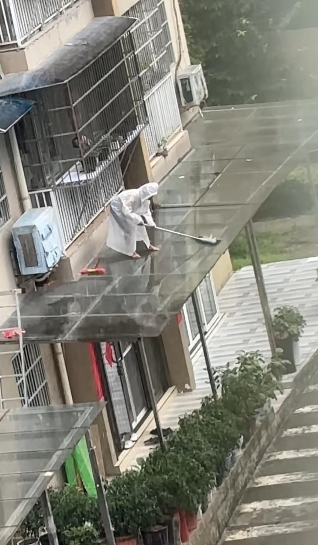 这位大姐在楼顶认真打扫卫生。大雨天🌧️有这个必要吗？没点安全意识啊？真不明白这
