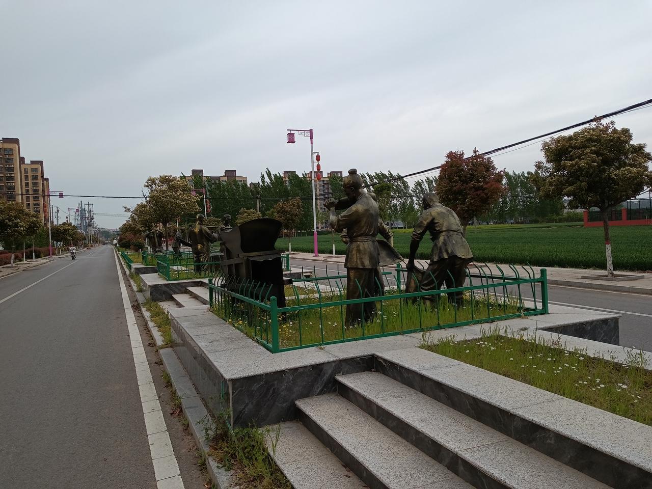 路上有几座雕塑，风景不错。山东肥城市桃园街景。