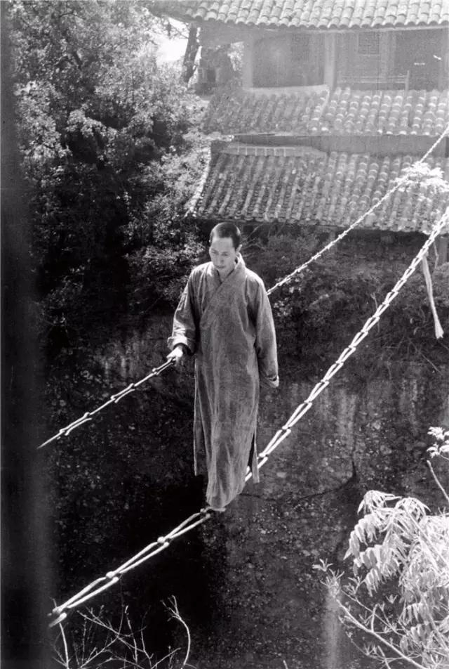 1930年代，四川江油窦团山上寺庙，一位僧侣以简易的铁索为桥，神色若定，步伐稳健