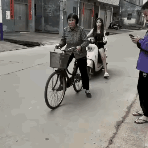 大妈在路上骑行自行车，当停下车来，回头一望，见一女孩骑行电瓶车紧跟着她，便顺势扔