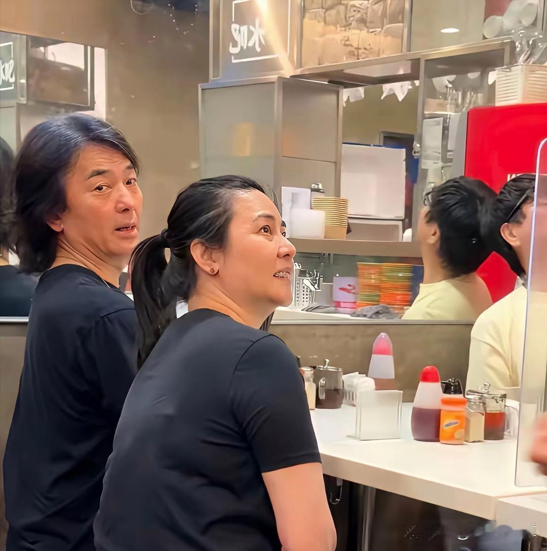 郑伊健与老婆蒙嘉慧坐在香港街头一家面馆吃拉面，52岁的蒙嘉慧素颜，穿着简单朴素，