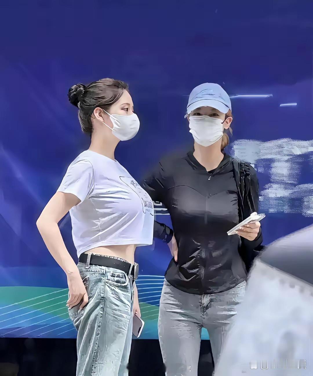 街头实拍，一位女生身着短款白色T恤，搭配牛仔裤。T恤版型较短，露出了一小截腰腹。