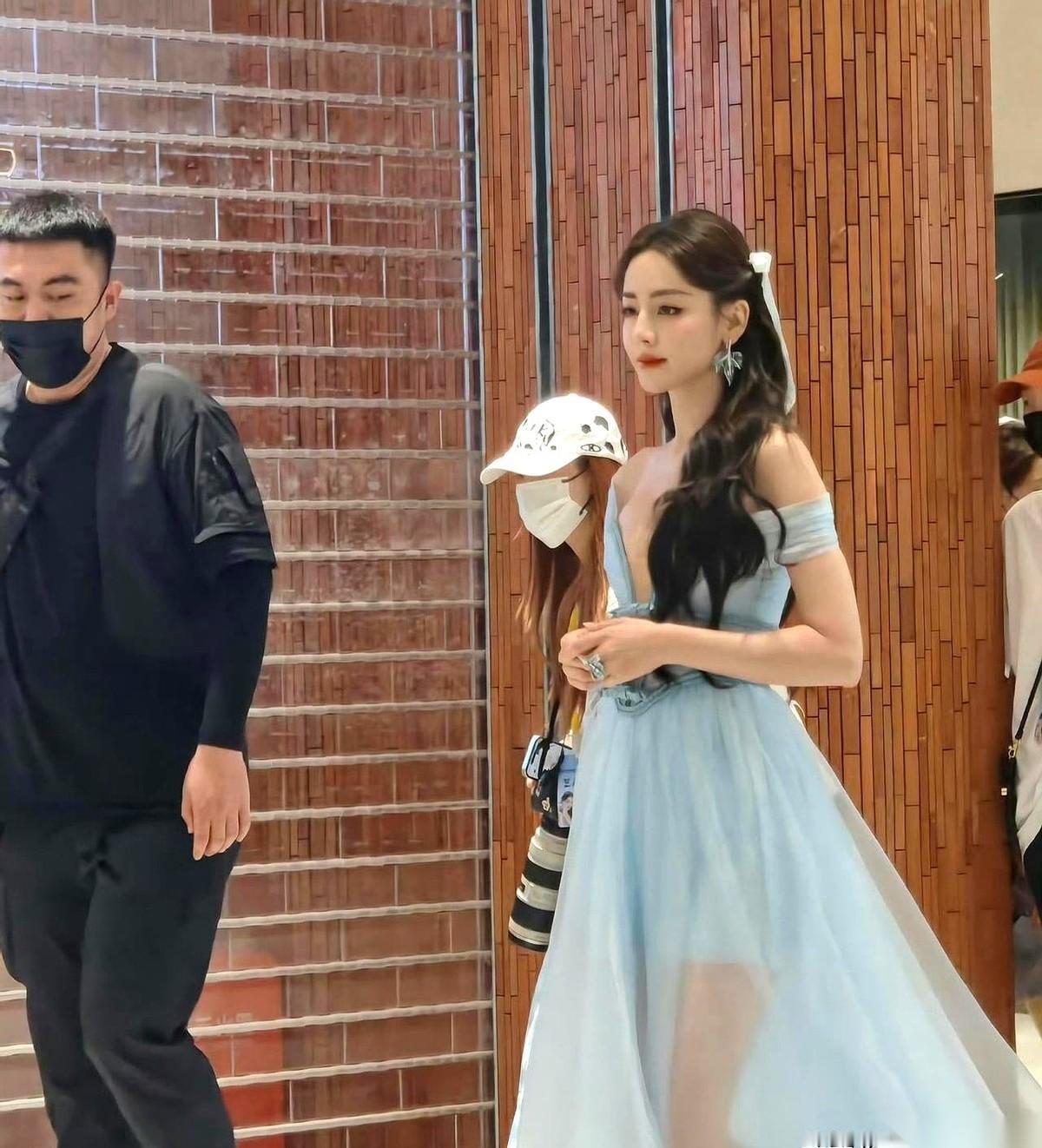 迪丽热巴7月6号出席品牌活动，一改往日习惯没再捂胸口。
可现场两道目光让她陷入尴