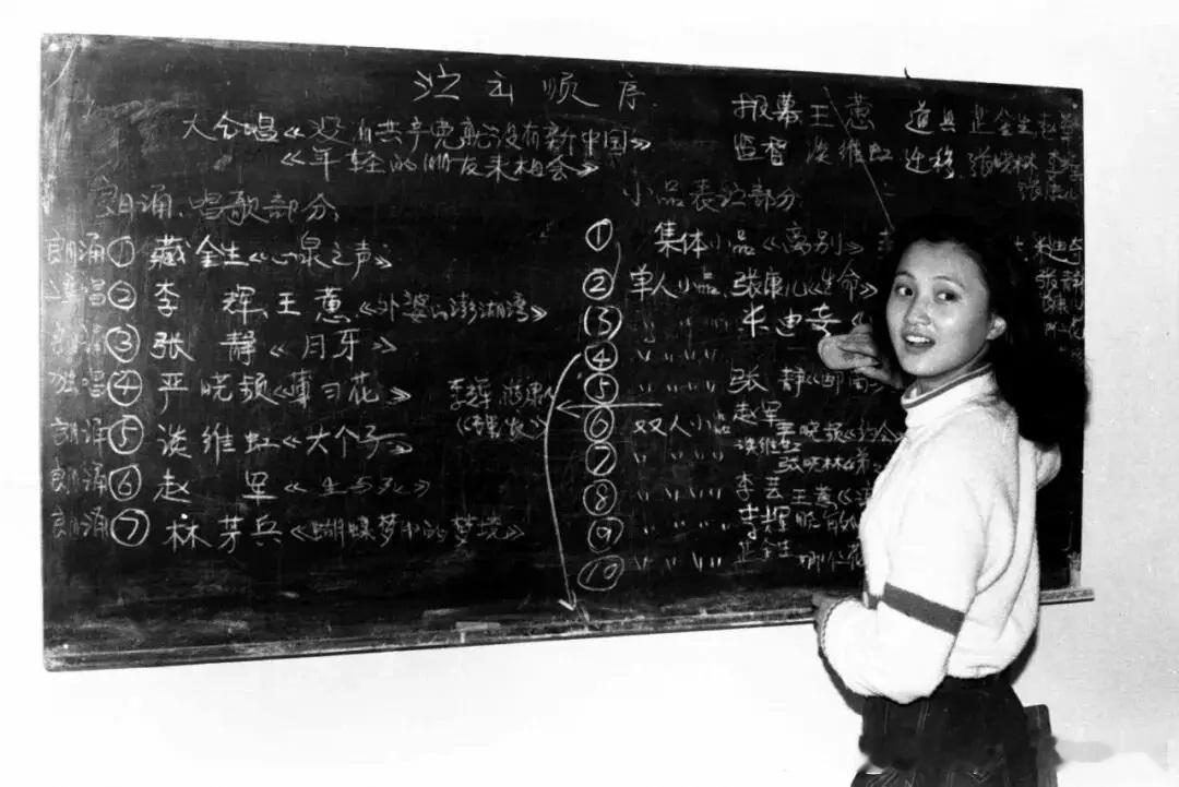 1982年10月表演系82班教室内，学生林芳兵正在擦黑板，黑板上是82班演出的节
