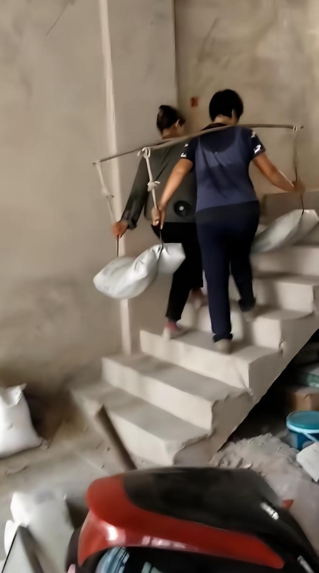 两人一同用扁担挑着两包水泥，这般挑法、这般协作，着实是我头一回见到，不由得让人对