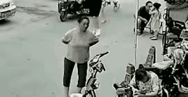 大妈双手叉腰在店门口聊天，好好站着没招谁没惹谁，一只狗突然冲过来，张嘴就狠狠咬在
