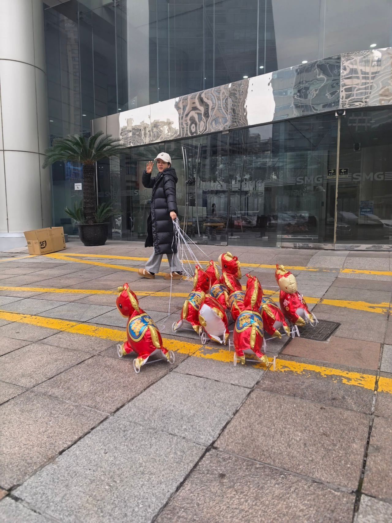 黄奕牵着9匹气球马上班 黄奕这波春晚上班路透太有趣了！身后9匹印着祝福语的气球马