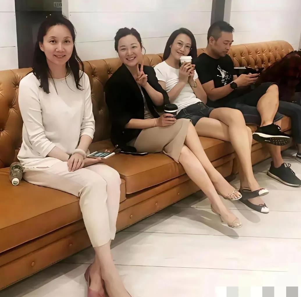 李修平和几位朋友聚会时的一张留影，一身简约白衣，坐在沙发上，手里拿着手机。李修平