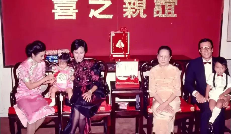 1983年，满一周岁的谢婷婷认汪明荃做干妈时的留影。
照片中的大人和孩子，大多都