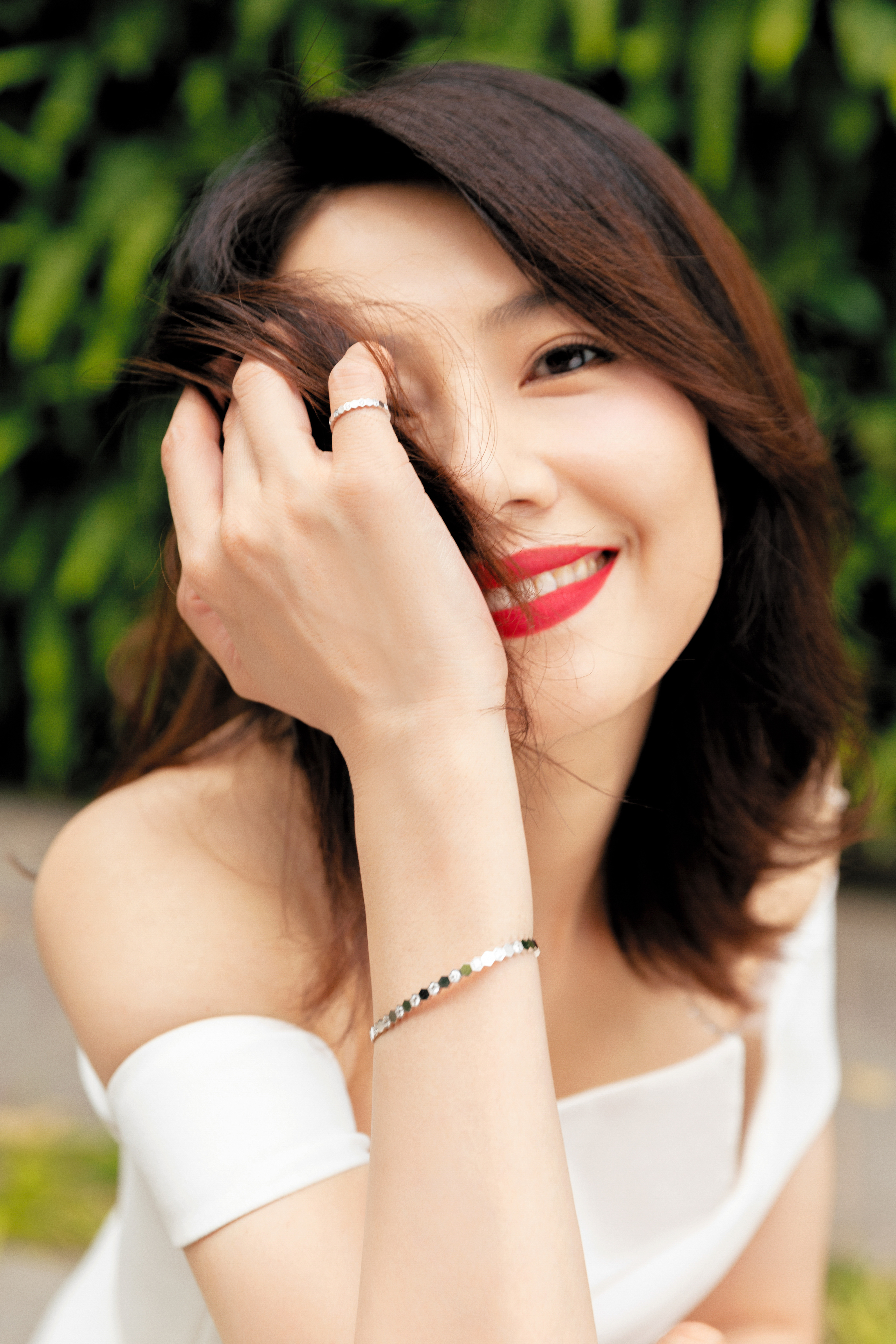 将简约高级的气质演绎得淋漓尽致。她身着白色一字肩礼服，利落的剪裁勾勒出优雅曲线，