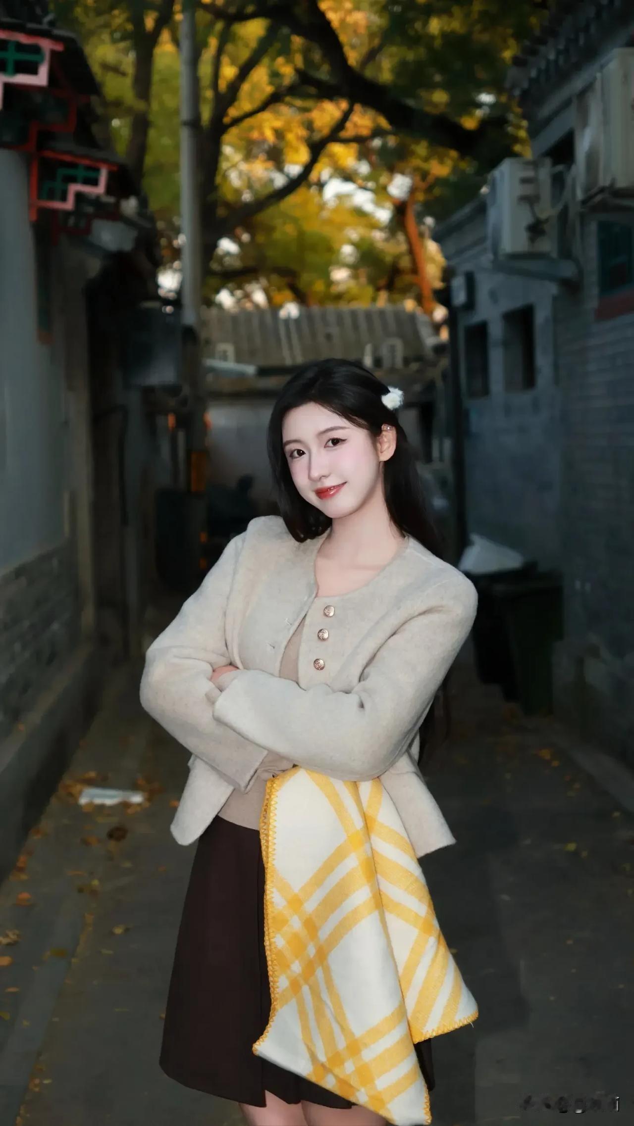 秋风乍起，落叶蹁跹，一位美人静静地倚墙而立，这画面堪称绝美。金黄的落叶在秋风中打