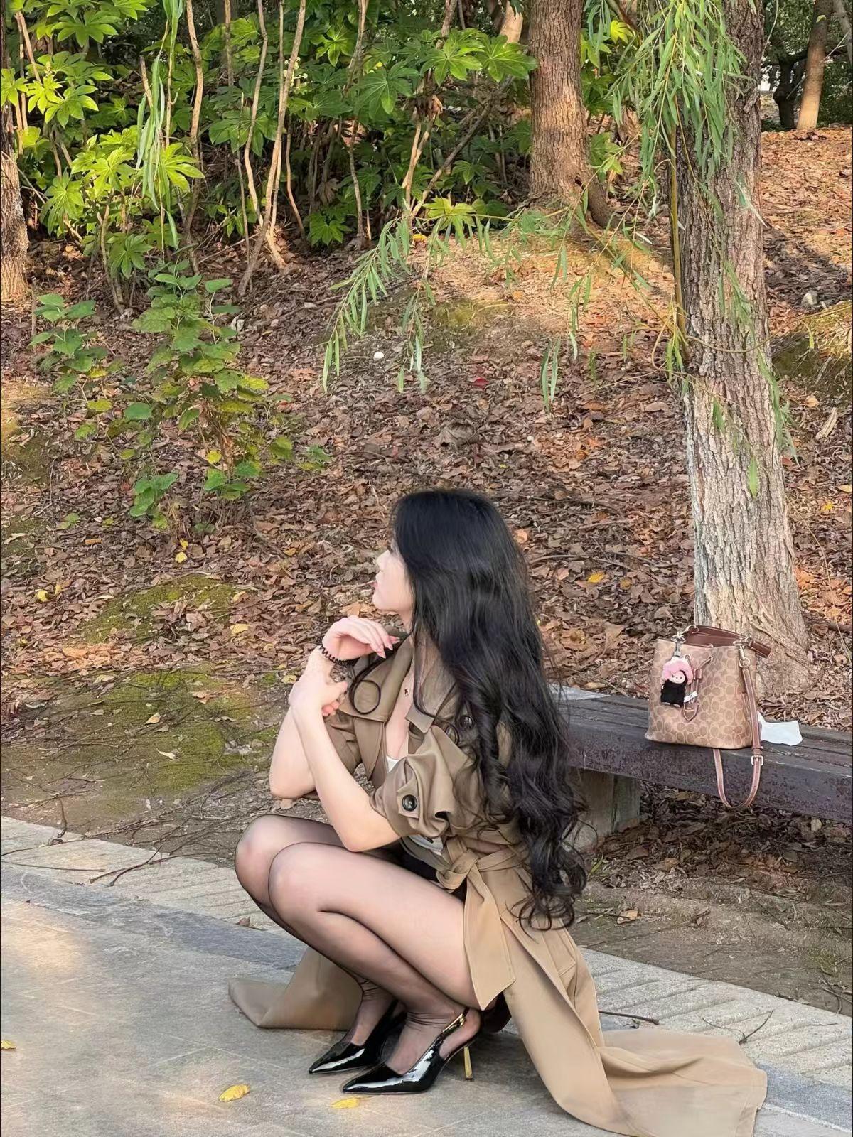 秋日森林中的优雅瞬间，黑发女子与时尚包包的完美搭配。