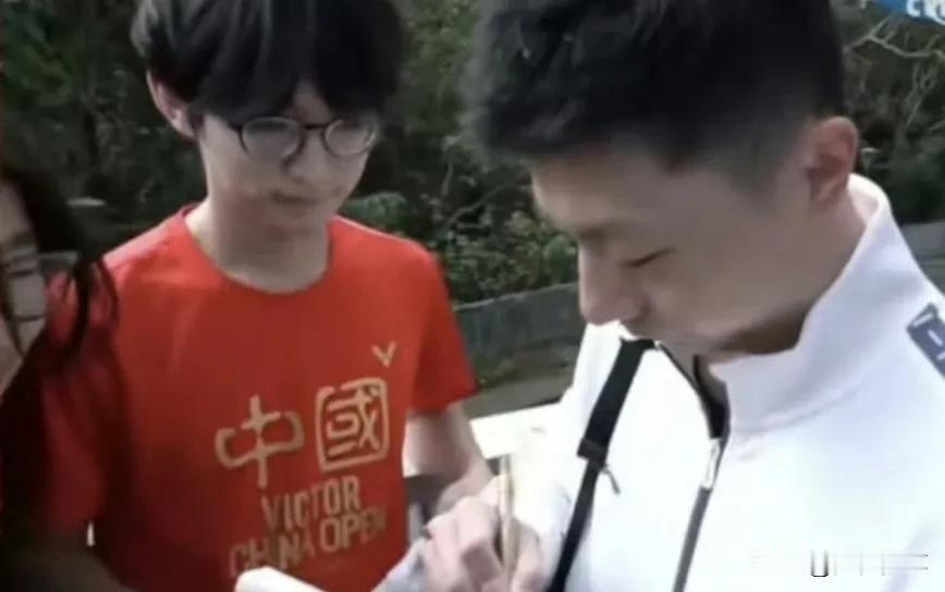 穿红色T恤等马龙签名的台湾学生估计要火了。

身穿红色T恤，手拿白色T恤，两件T