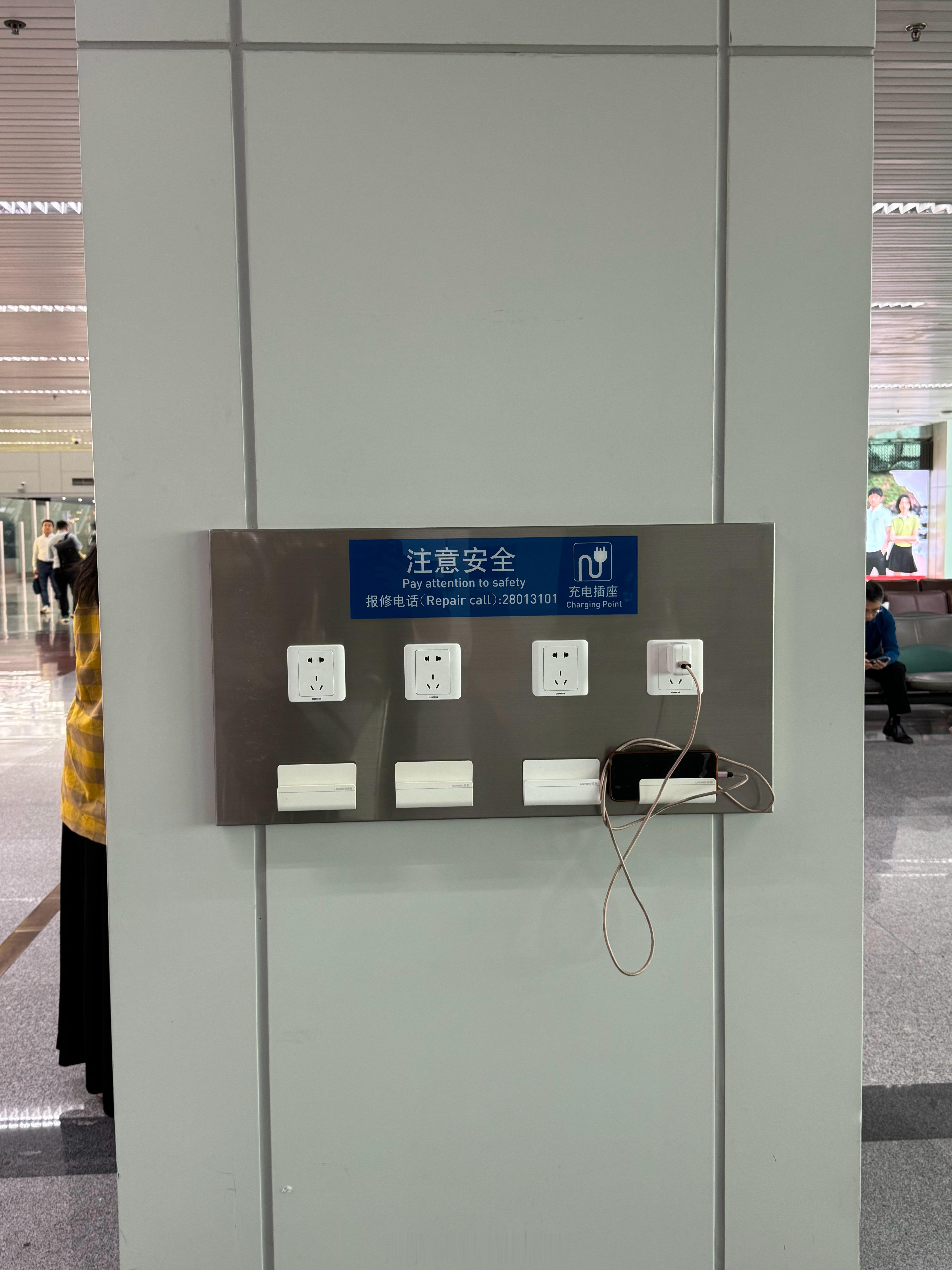 福州机场的充电位设定有点特别，就一堵墙。墙上有几个插座，下方提供了一个绿联的支架