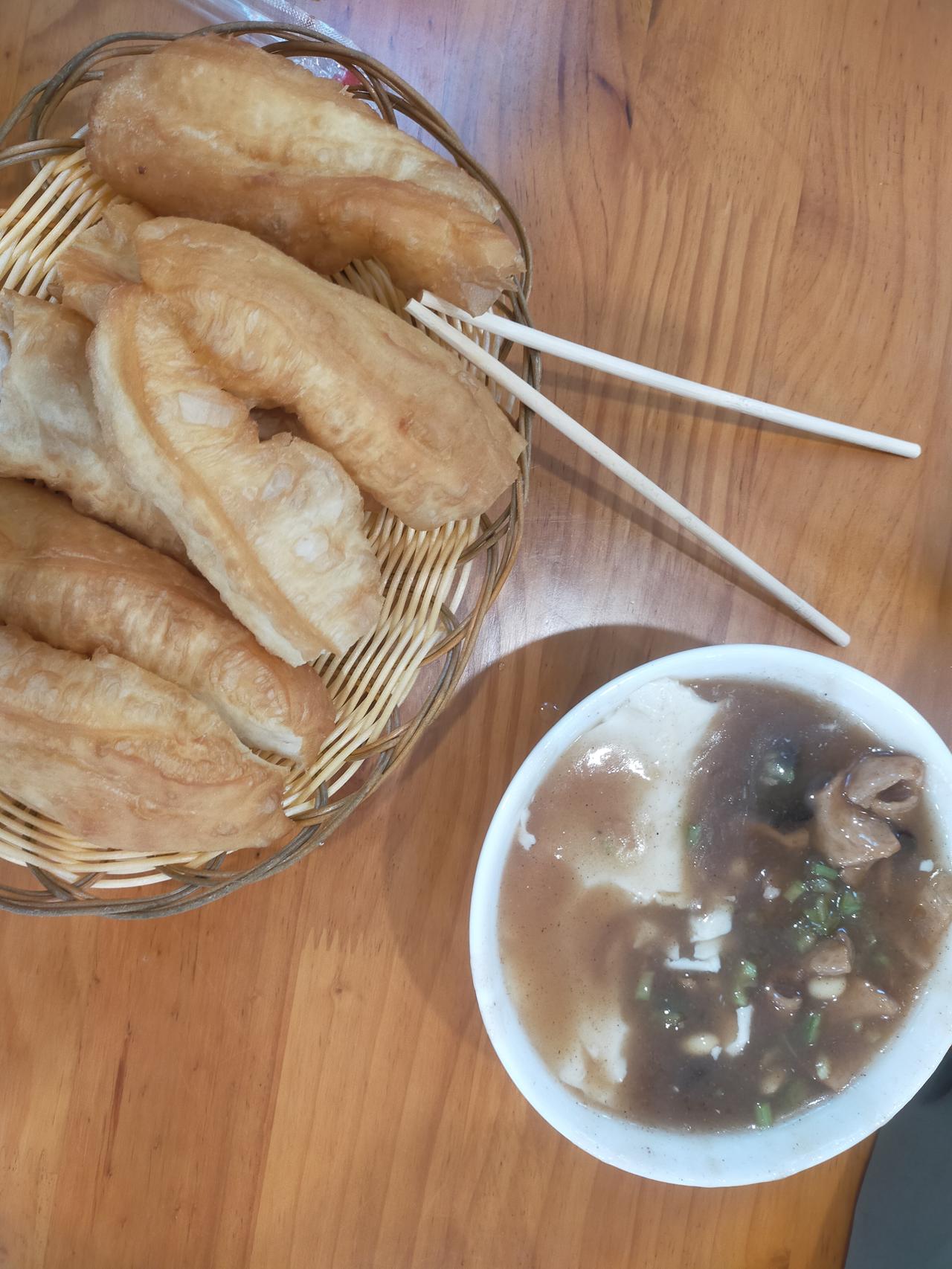 这早饭也太是那个了！竹篮里炸得金黄的油条，油亮亮的看着就香。旁边那碗豆腐脑绝了—
