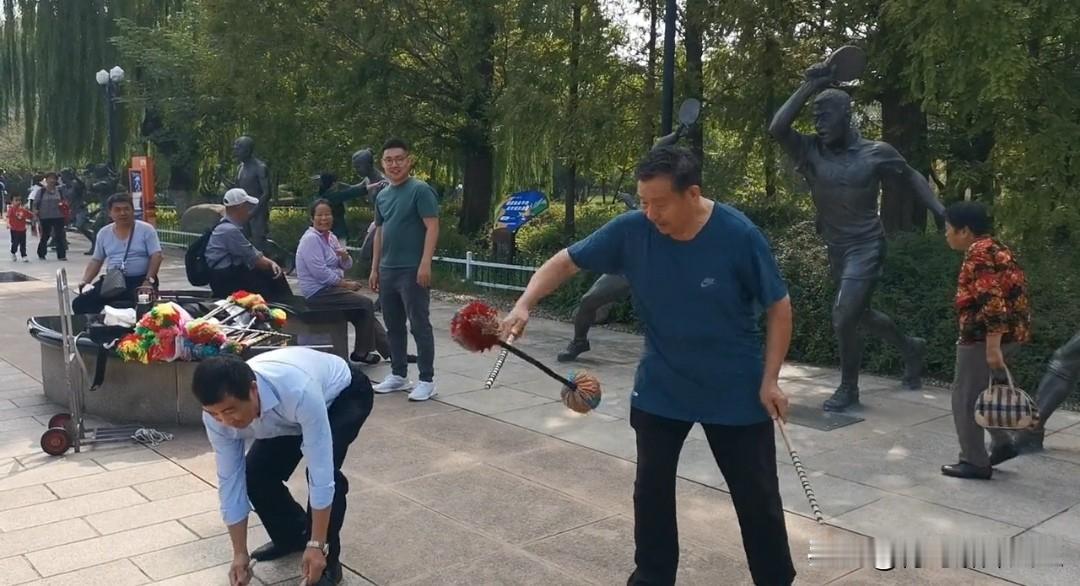 公园里两位老师在表演传统打花棍，动作娴熟流畅。
这项老民俗健身技艺，如今越来越少