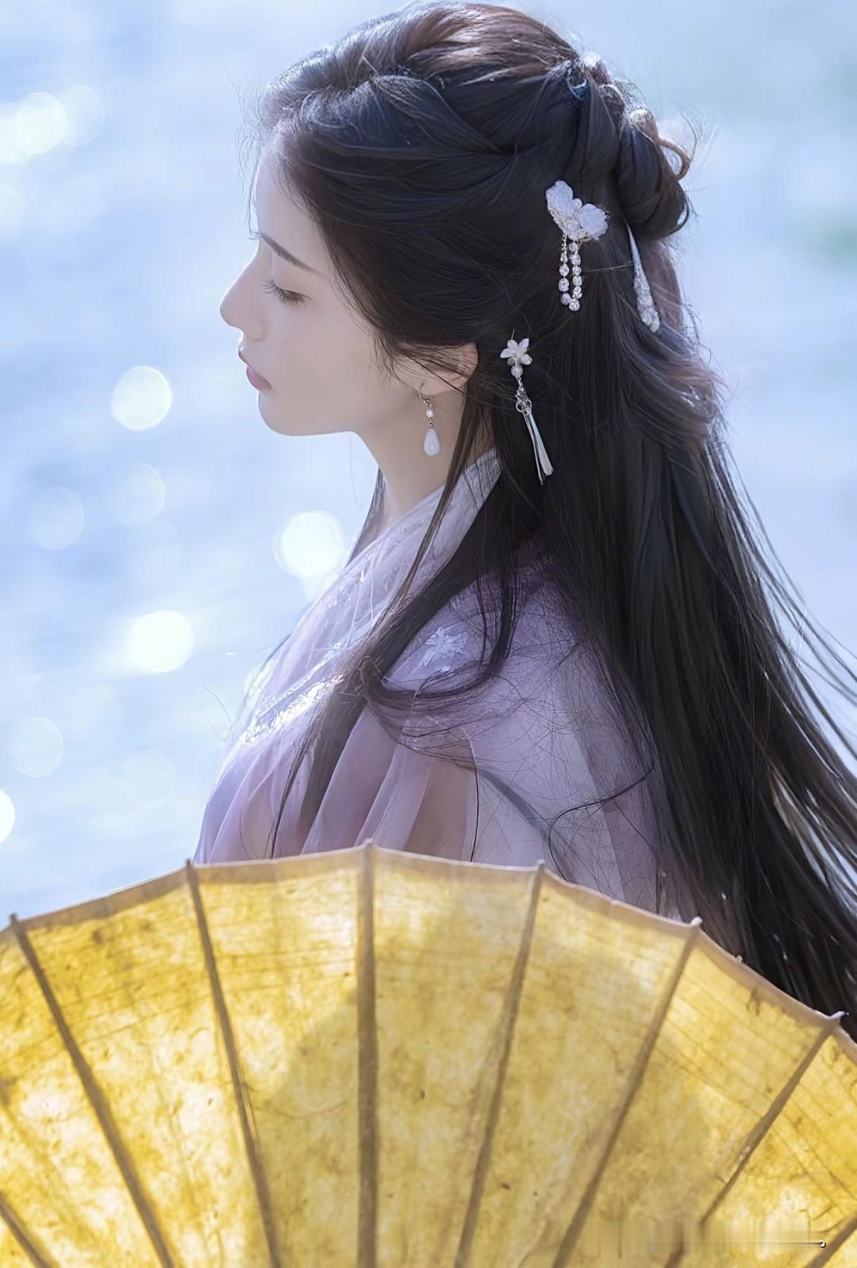 像是从山水画里走出的仙子。
身畔是碧波荡漾的江水，
身后是连绵起伏的青山。
不需
