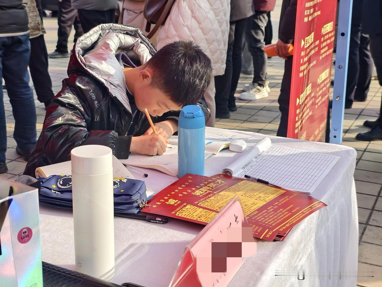 大人在安康金州广场上开会，孩子就在旁边自己做作业，这大概就是人们常说的别人家孩子