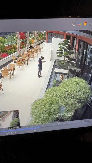 监控摄像头拍到一名餐厅女服务员只顾低头玩手机。
结果一脚踩空，一不小心跌进前方的