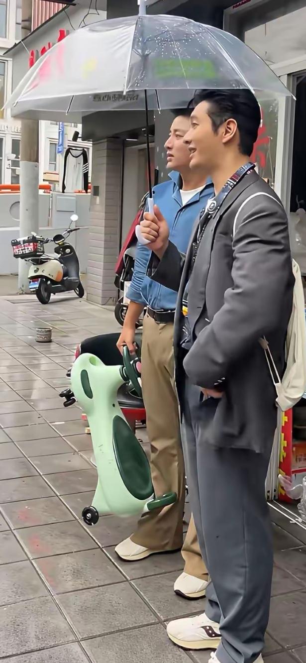 撑着伞的两位演员，别说哈，看上去就是比普通人帅，能认出来是谁吗？
