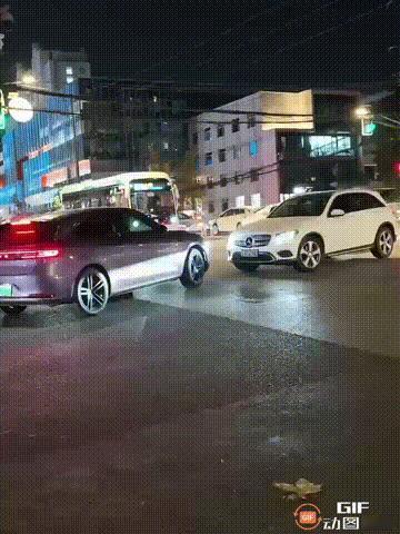 一处街头，一辆即将左转的紫车，遇到了直行的白车，双方迎面对上，却谁都不愿意让路，