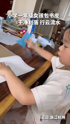开学第一天，一段视频火了。
一个刚上一年级的女孩，坐在桌前，自己给新课本包书皮。