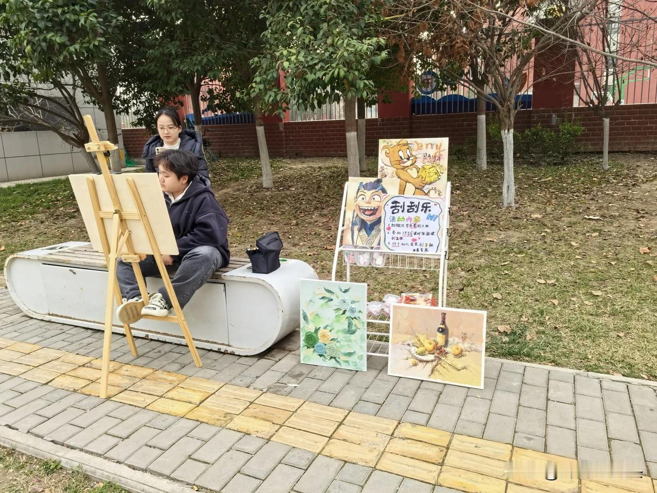 昨日，在沣东新城一学校门口人行道上，小编看到一女孩坐在路边的櫈子上，正聚精会神地