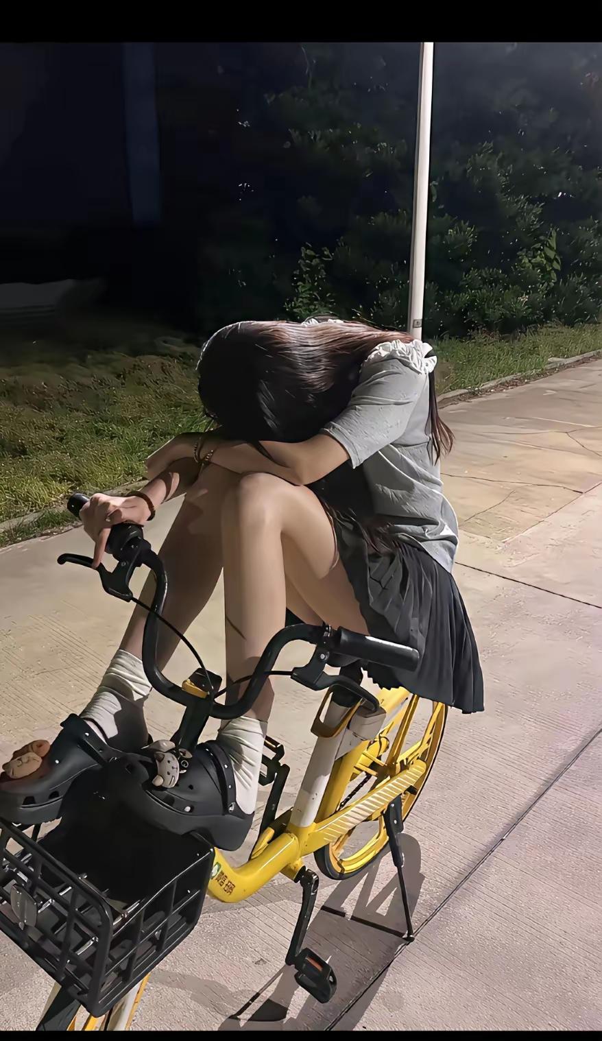 生活有太多的无助，女子怕是遇到烦心事了，趴在自行车上静静的思索，这社会太难了。