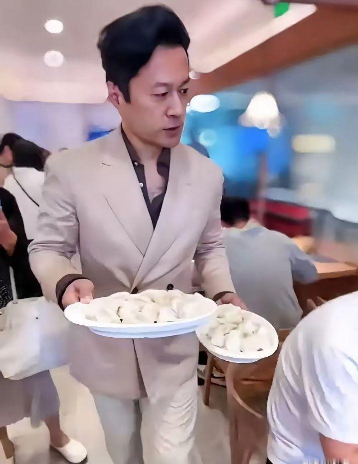 好家伙！西装革履，打扮得板板正正，手里端着两大盘饺子，你敢信这是荧幕上气场十足的