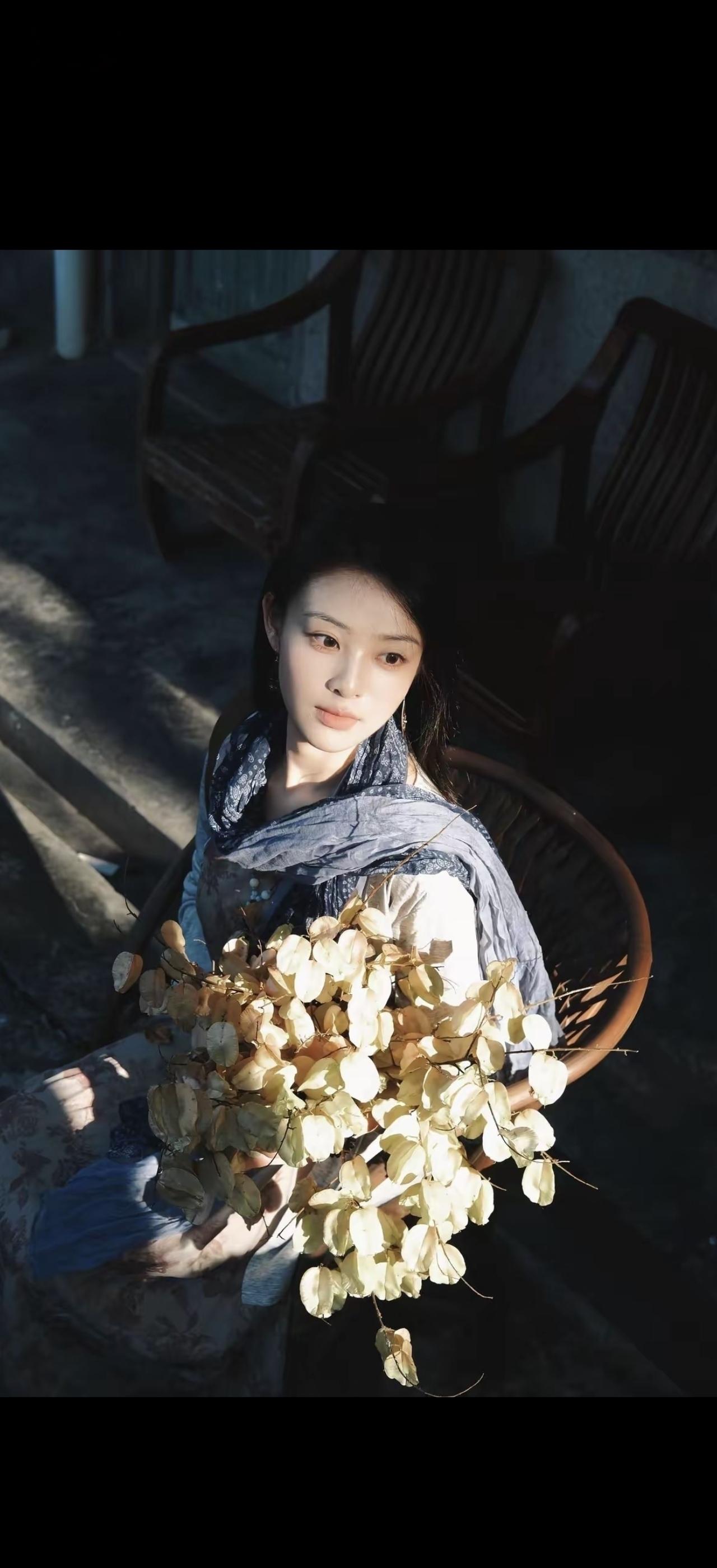 一个女孩抱着一束花坐在椅子上。