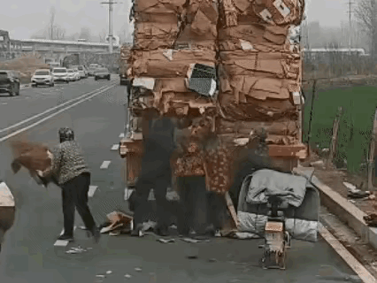 装载废旧纸箱的货车，不知什么原因，停在了公路边，几名附近的村民上前撕扯车上的纸壳