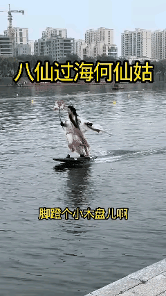 这个女子滑水的本领挺厉害的，她站在这个小船上，手里还拿着一朵花，身体的平衡保持的