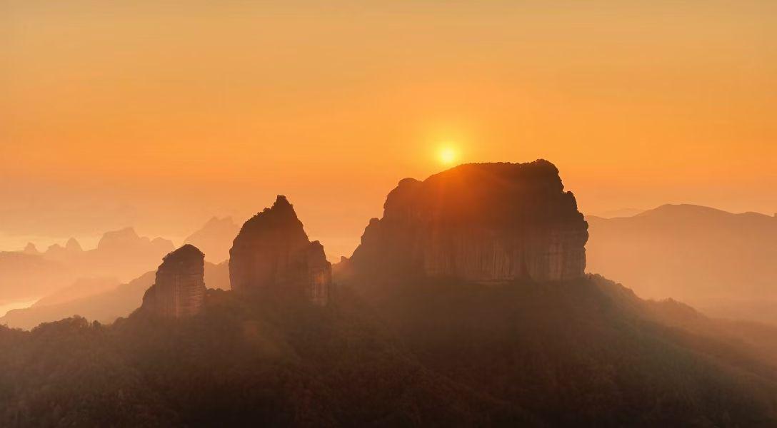 一轮金日沐丹霞，七彩斑斓地貌奢。
万壑参差缭碧雾，千山妩媚着红纱。
虽经霜雪几侵