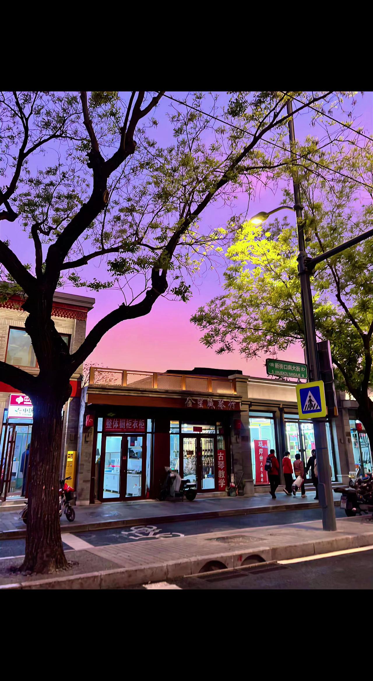🌆暮色给老街镀了层糖霜🍬，树影是时光的墨痕，行人把故事走成了诗✨