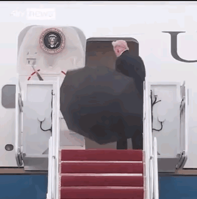 特朗普竟然还是不会用伞。
这把伞应该是由工作人员打开，然后递给特朗普的。因为特朗