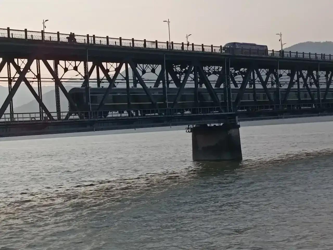 傍晚时分波光粼粼的江水、绚丽多彩的晚霞、壮观的钱塘江大桥和绿皮火车相互构成一道风