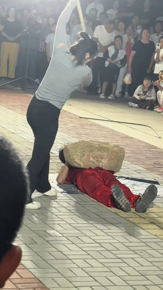 一对夫妻在街头广场上表演“胸口碎大石”？
结果表演失误，压在男子身上的石头并没有