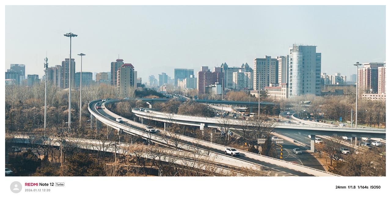 冬日午后北京，城市天际线被阳光削得锋利，写字楼的窗缝漏出暖黄的光，与街面的冷白撞