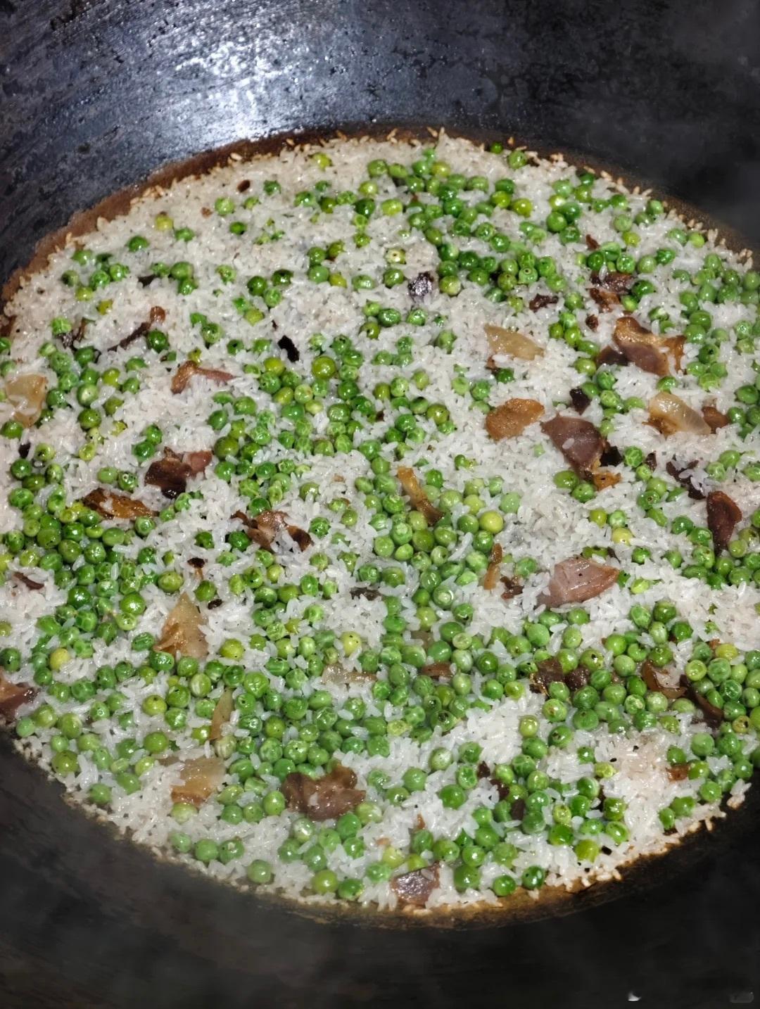 铁锅焖的豌豆腊肉饭，用烟火气焖出来的家常味道。灶膛里的柴火噼啪作响，油润的腊肉先