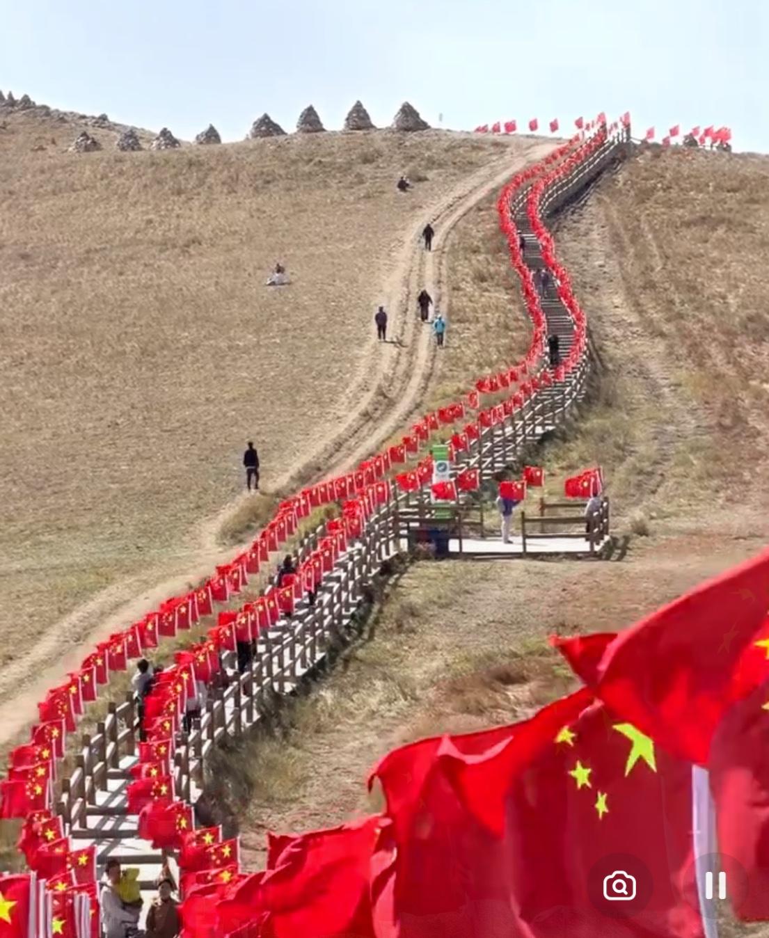 山巅之上，五星红旗猎猎作响。风裹着山河的壮阔，撞进每一个仰望者的心底。这抹红，是