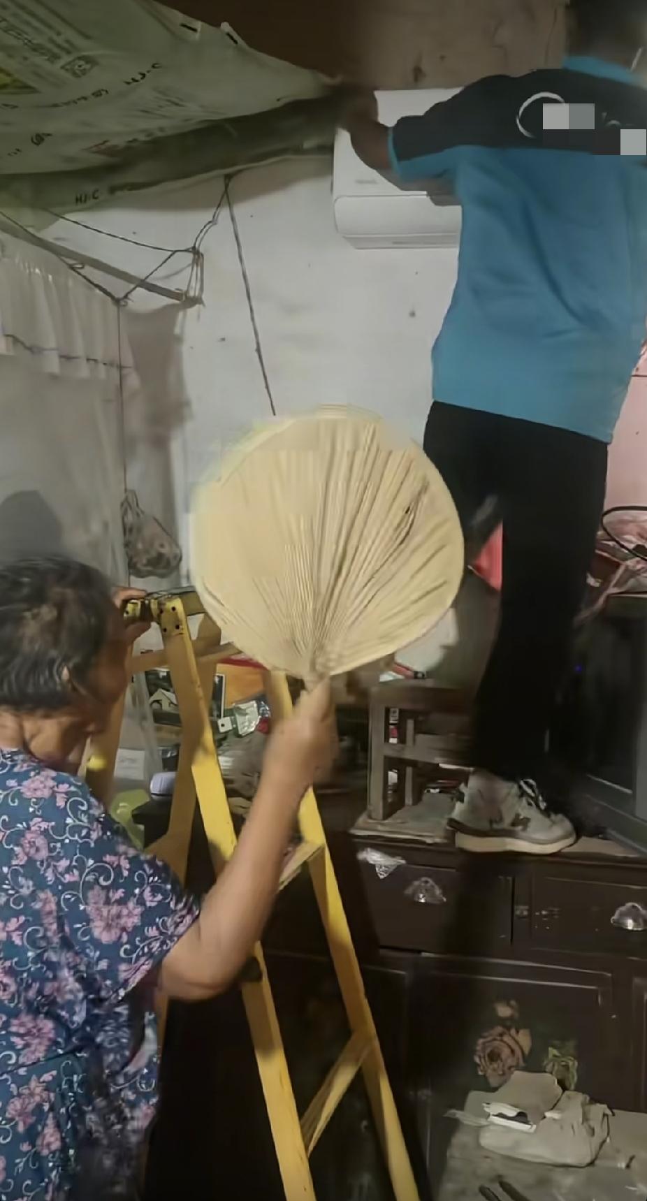 一位安装空调的男子，正在挥汗给客户安装空调，旁边老奶奶的一个举动，看着让人感动暖