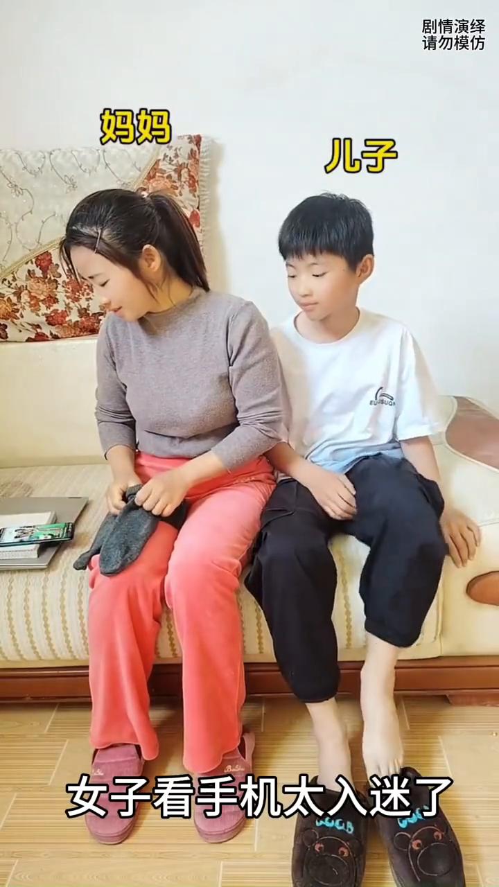 妈妈看手机入迷去穿袜子，谁知她穿儿子脚上都不知道。
女子看手机太入迷了，只见她准