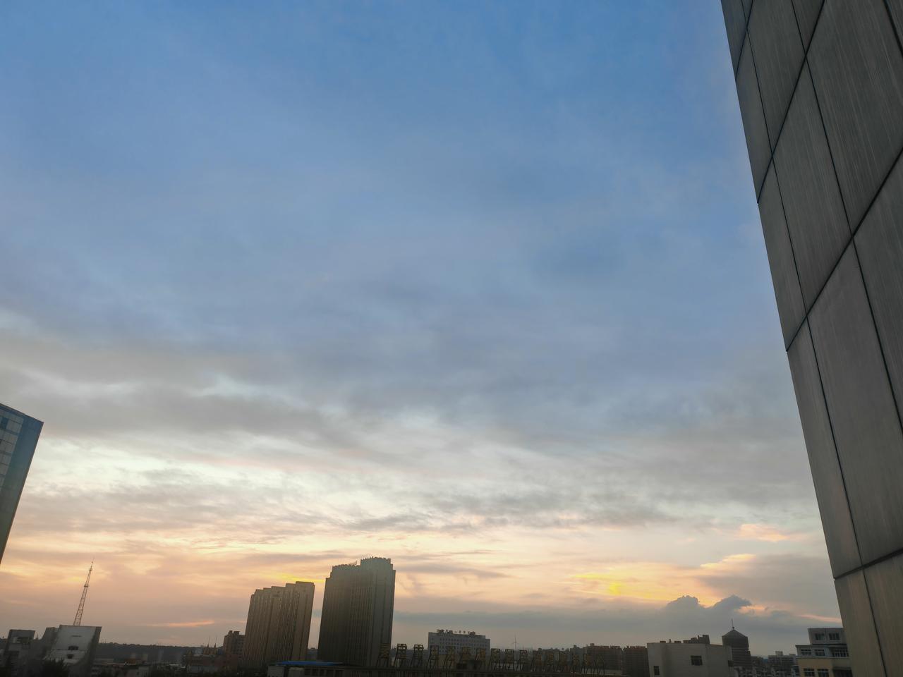 分享一张傍晚的天空照片暮色缓缓笼罩城市，漫天云彩晕染出柔和的暖调霞光。林立的楼宇