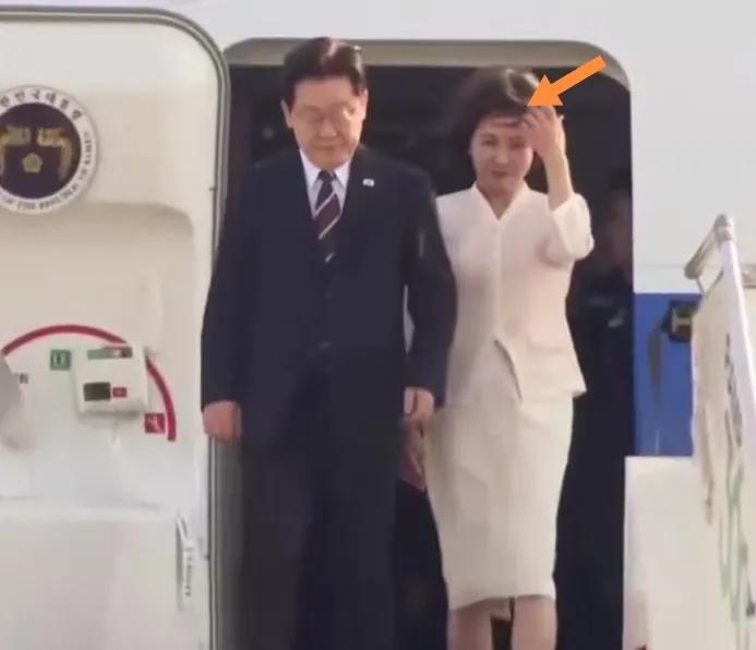 李在明携夫人访问印度走出飞机舱门起大风吹乱头发。