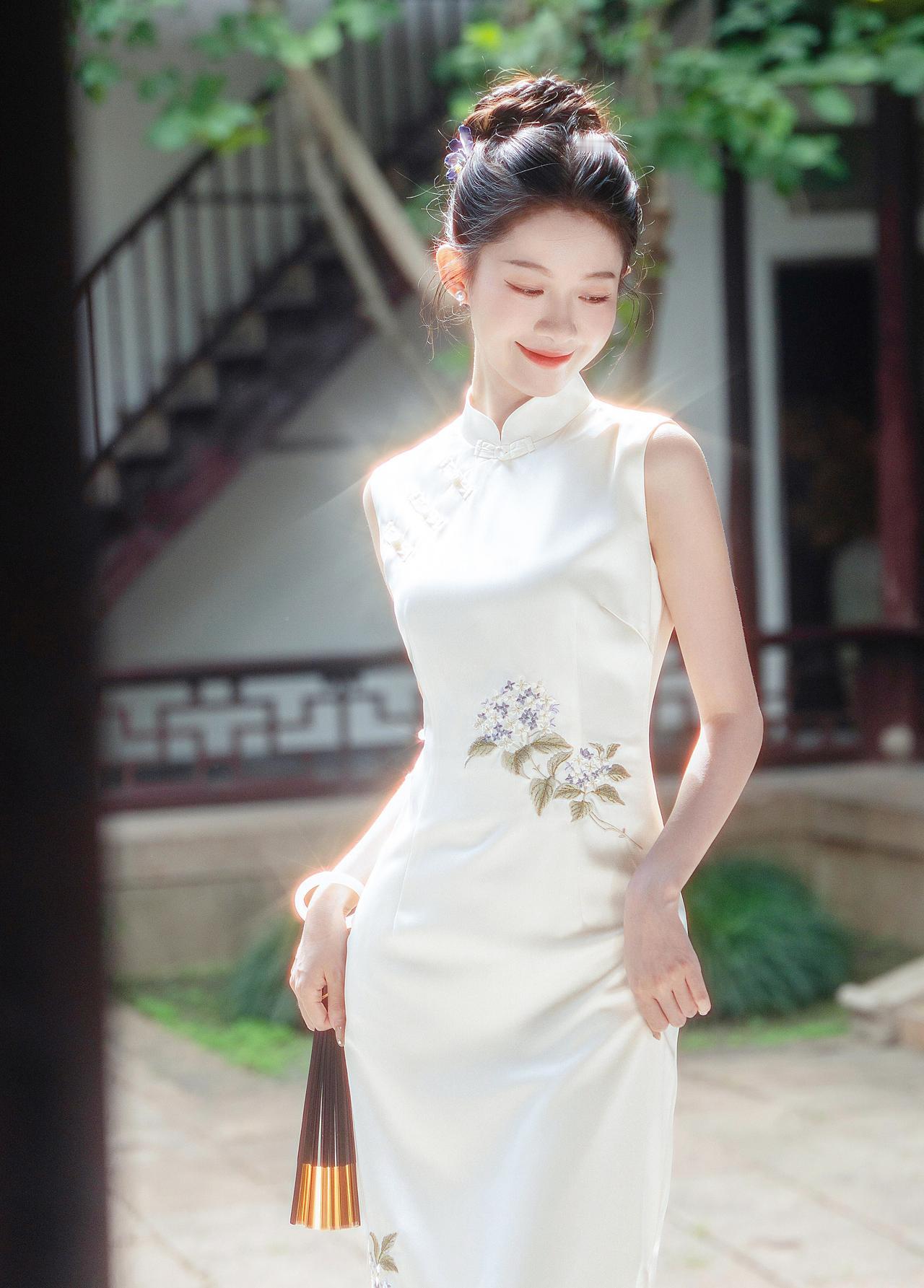 晴光一缕落襟边，白缎裁云绣紫妍。
团扇轻摇庭榭里，江南风韵入眉弯。