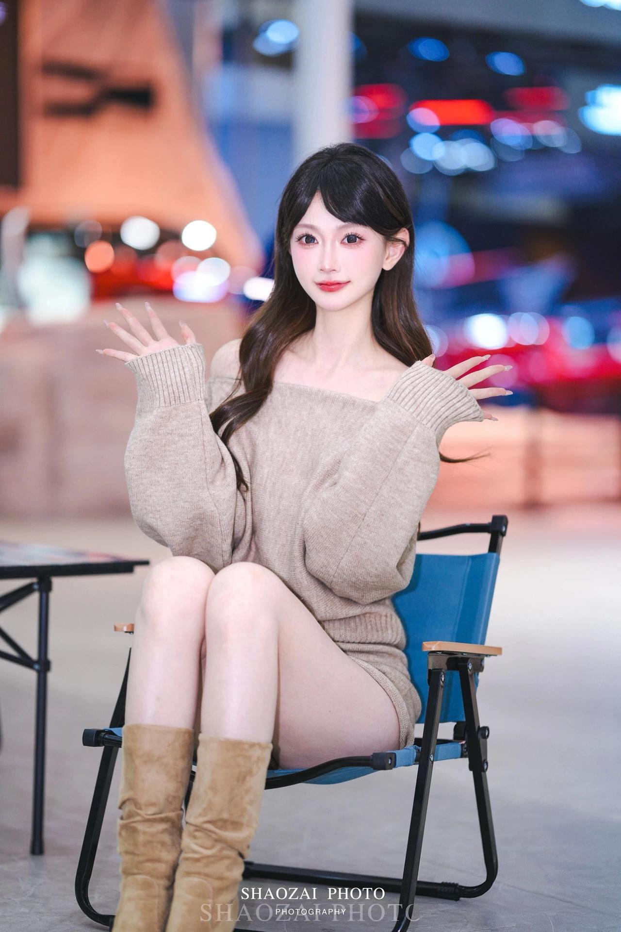 她有着一头柔顺的深棕色长卷发，自然垂落在肩头，空气刘海衬得脸庞愈发小巧精致。一双