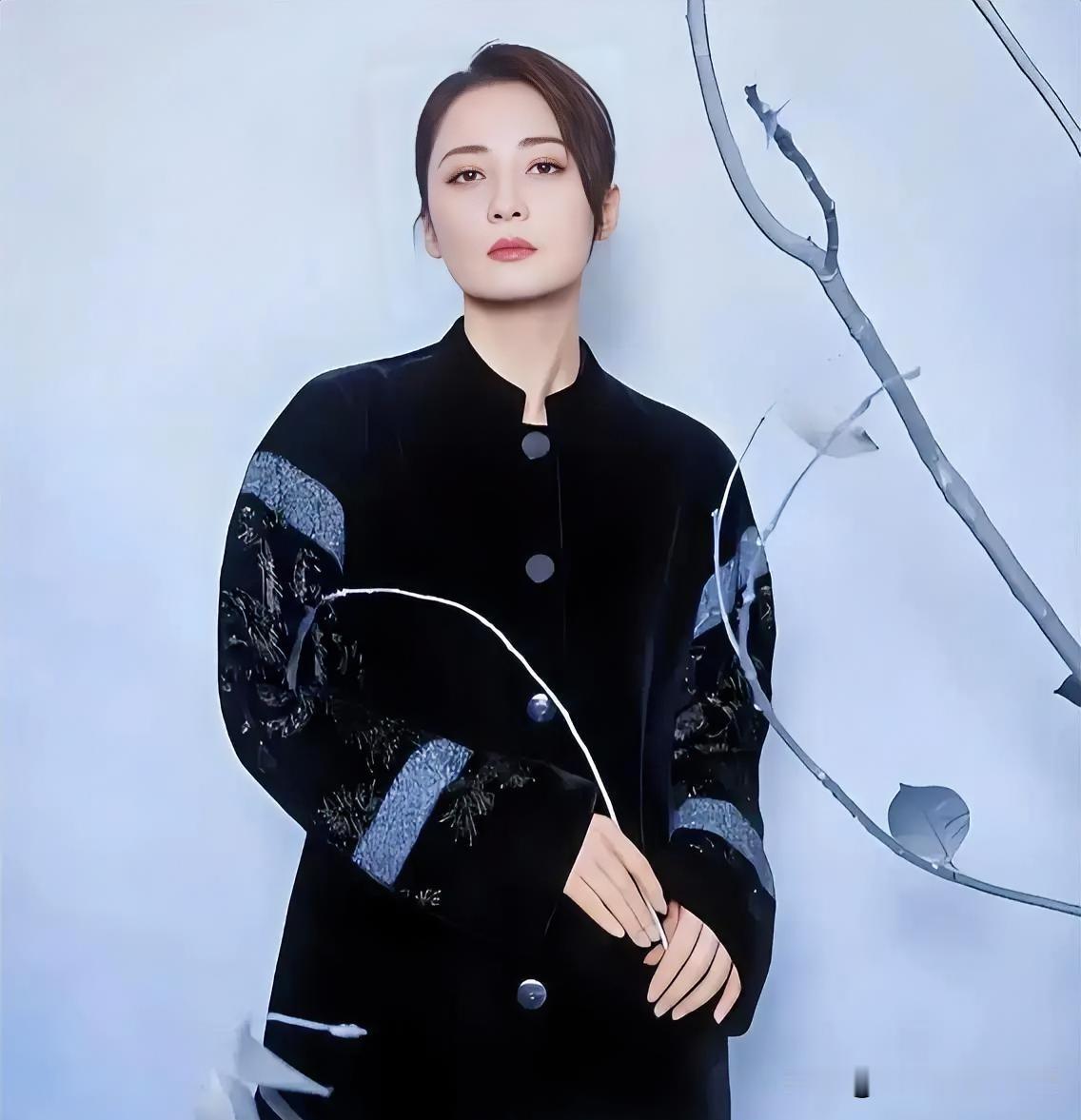 墨色华服凝古韵，立领藏雅致，袖间纹样诉风华。她眸含清光，于素白背景前静立，似一幅