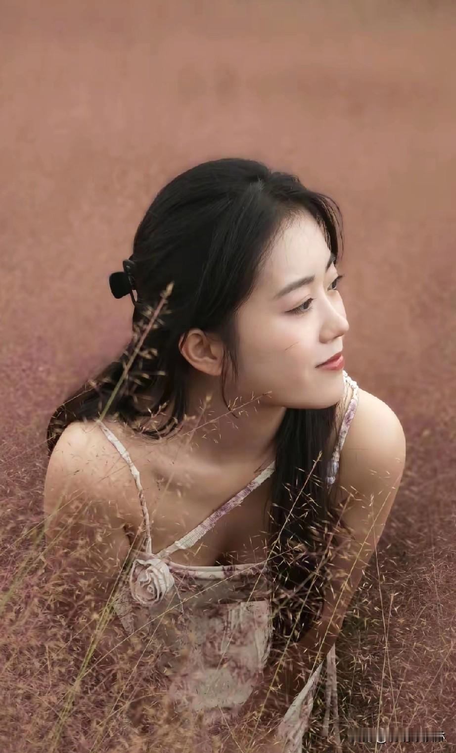 在田野中沉思的少女，花裙随风飘动，仿佛置身于梦幻世界。