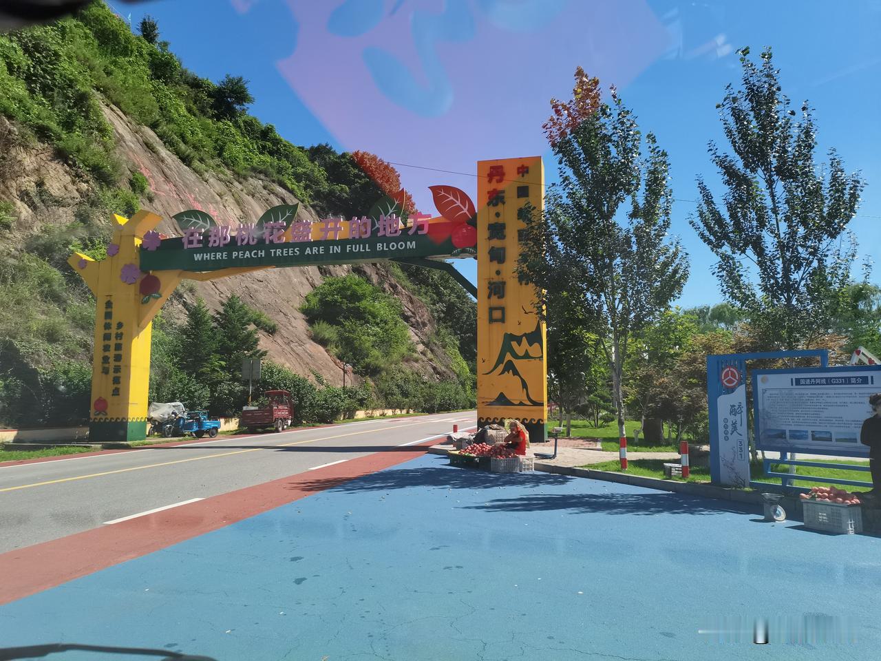 平整的柏油公路穿梭在连绵的青山之间，道路两旁绿植繁茂，路边盛放着成片野花草，行车
